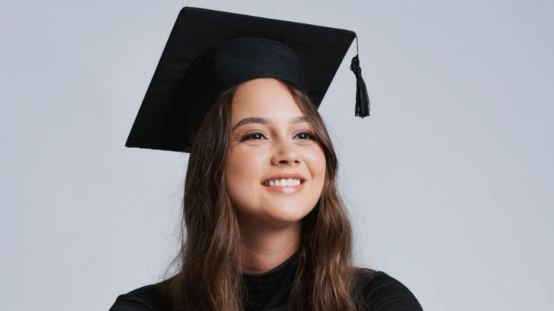 Estudiante sonriendo en su atuendo de graduacion.